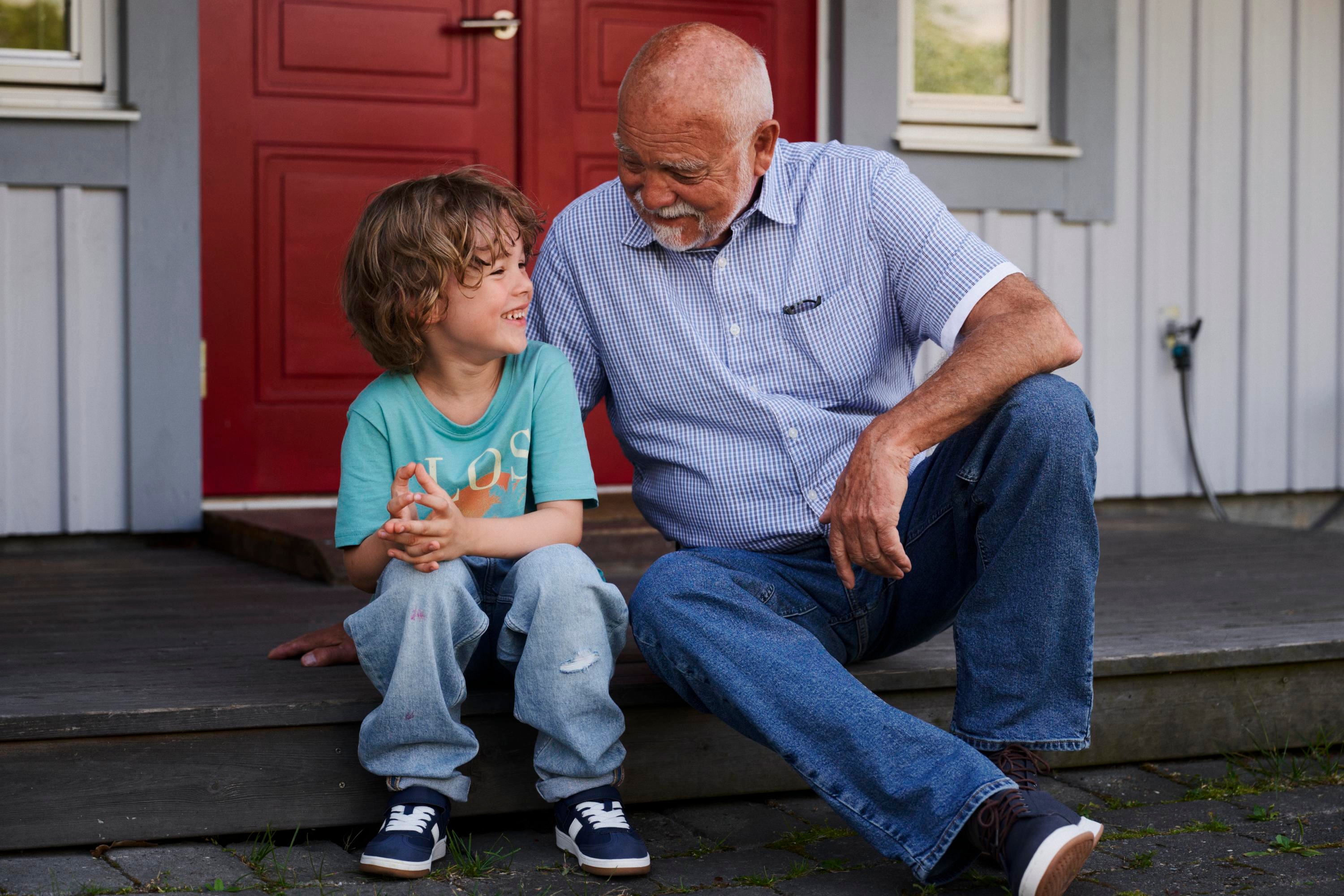 Ett barn och en äldre man sitter på en trappa och pratar