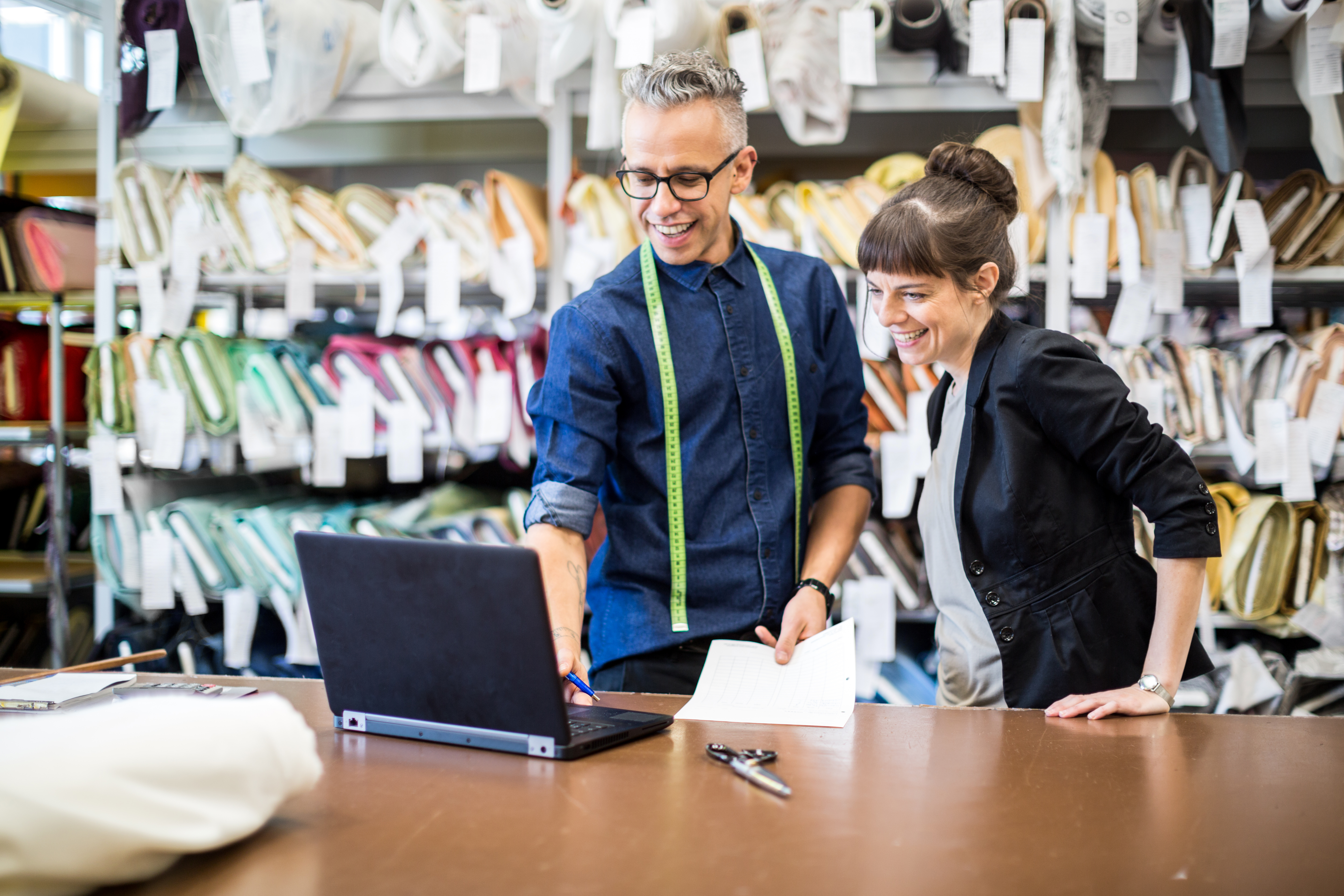 Man och kvinna står tillsammans vid en arbetsbänk och tittar på en bärbar dator