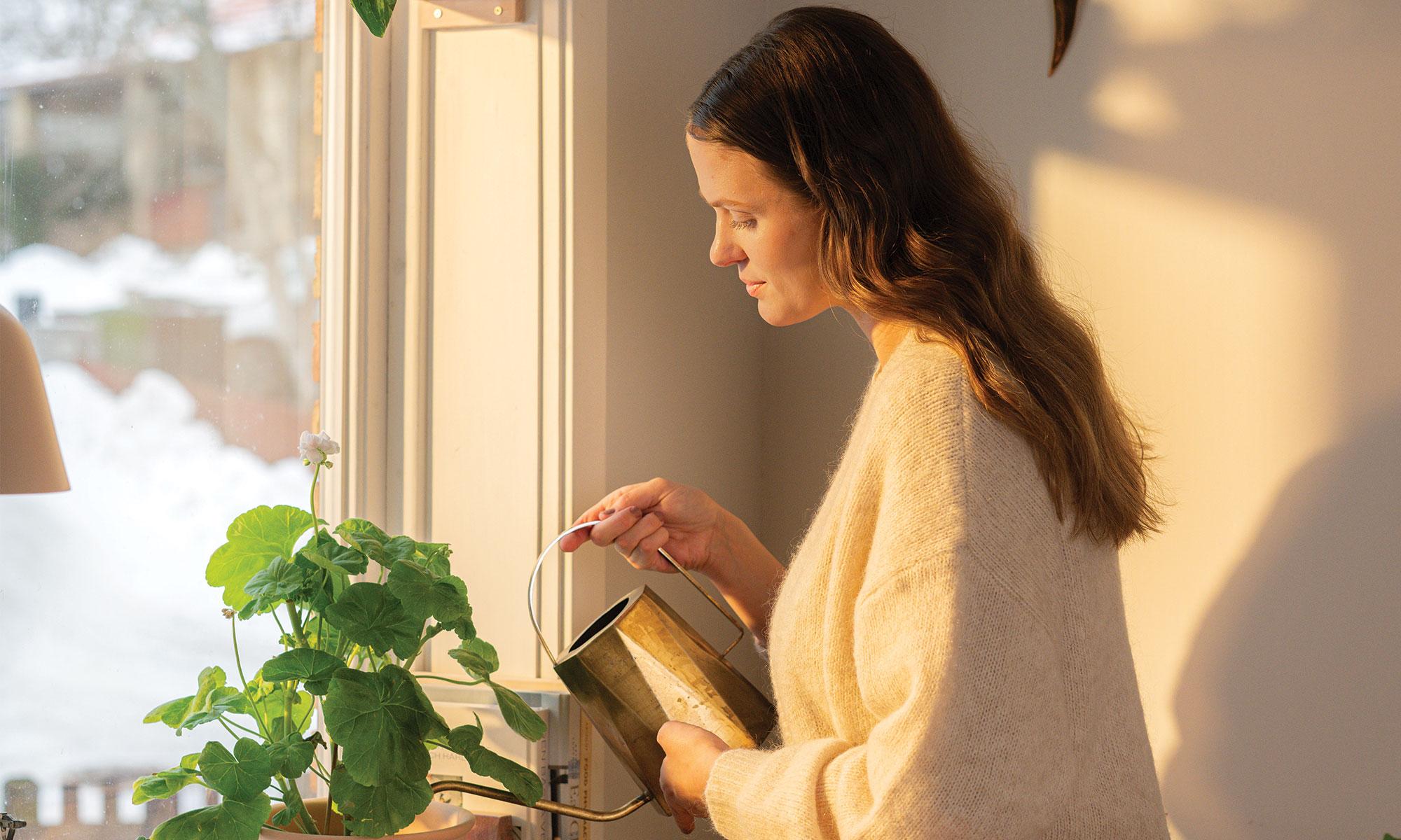 En kvinna som varsamt vattnar sina blommor.